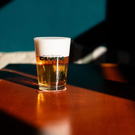 Um copo de chopp Brahma com colarinho alto, sobre uma mesa de madeira.